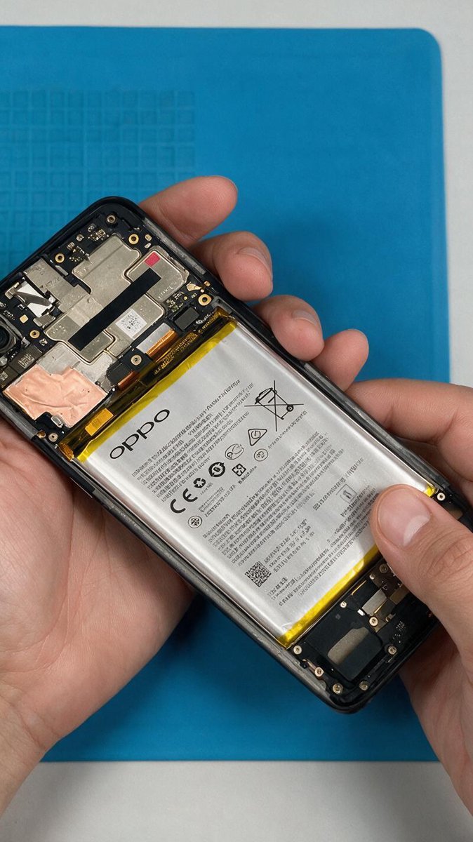 Reconstructed teardown of an opened Android phone with its large battery exposed on a work mat