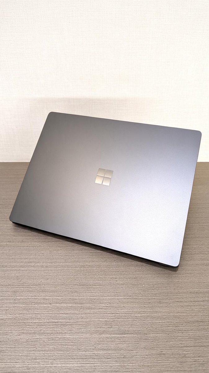 A closed silver Surface laptop on a wooden desk