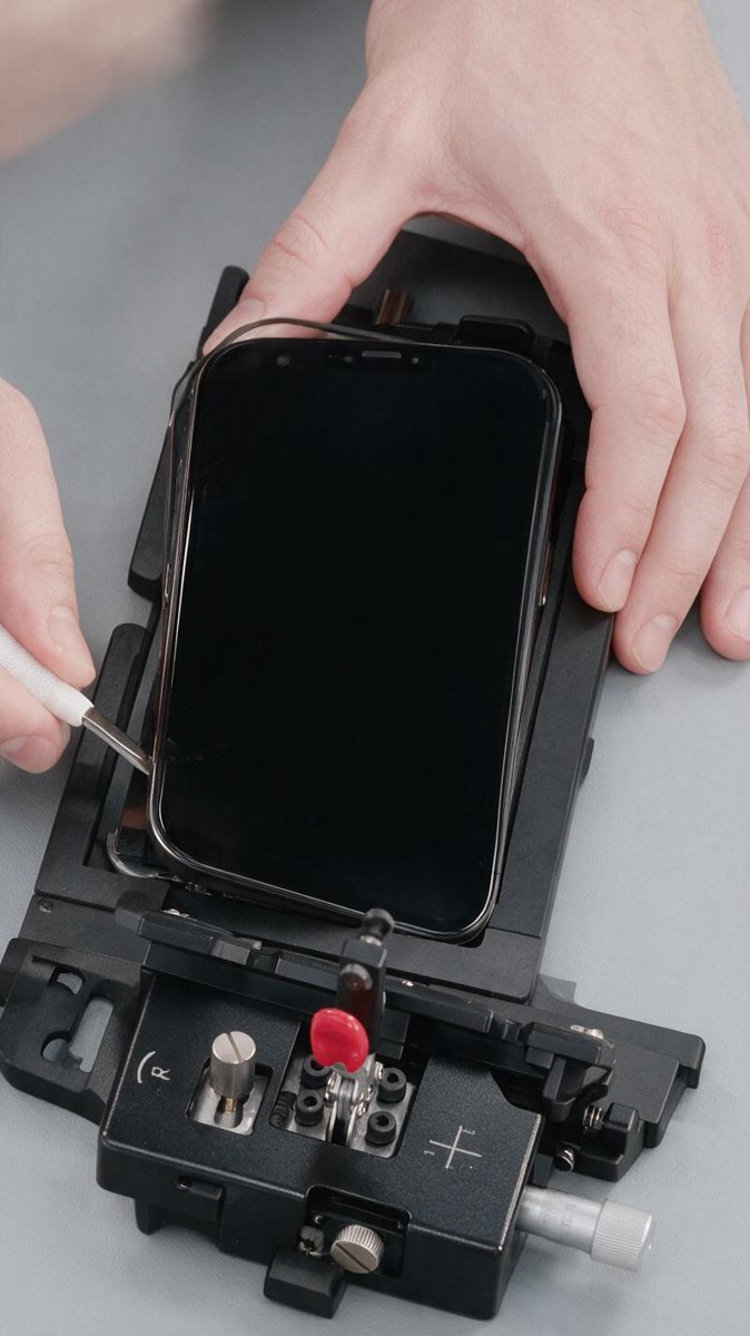 Technician disassembling an iPhone with repair fixture tools